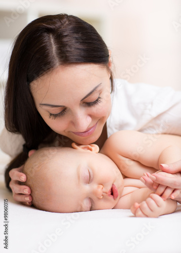 Happy beautiful woman looking at sleeping son baby