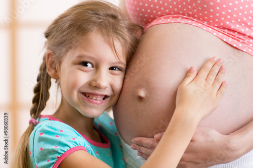 Child girl hugs belly of he...
