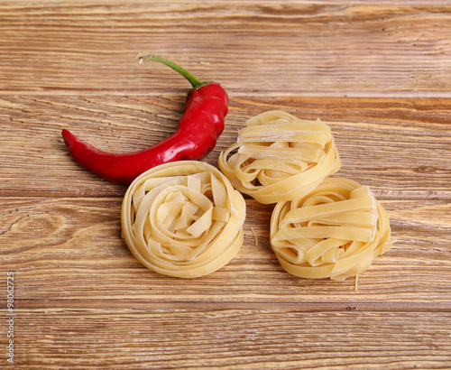 Pasta spaghetti noodles with chili peppers on a wooden table