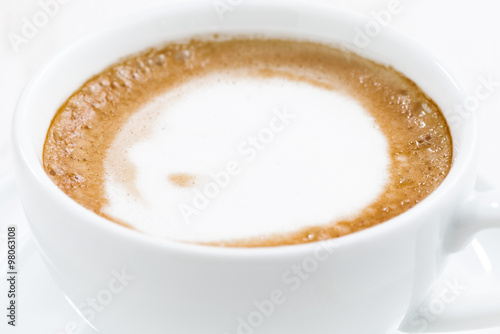 cup of cappuccino on a white wooden table, closeup