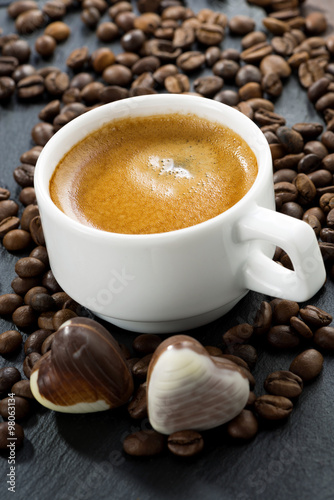 cup of espresso, coffee beans background and chocolate candies 