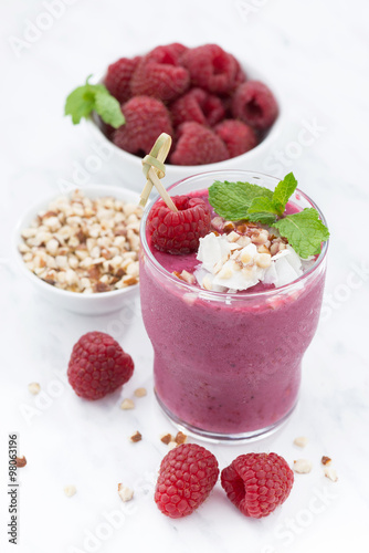 Fresh raspberry smoothie with nuts on white background, closeup