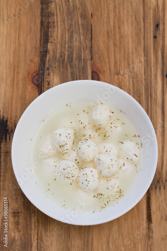 mozzarella with herbs in white plate on white wooden background