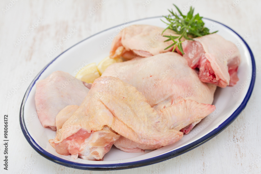 raw chicken on dish on white wooden background raw chicken on dish on white wooden background
