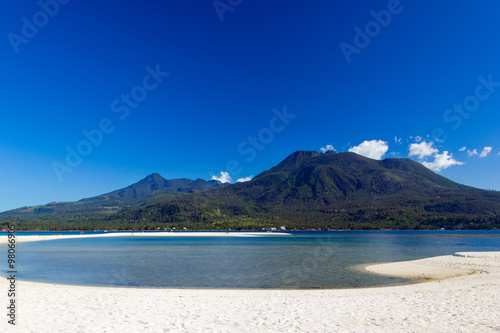 Island with white sand and volcano in the background