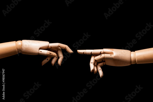 Two hands of wood parody the birth of Adam by Michelangelo. Isolated on black background.