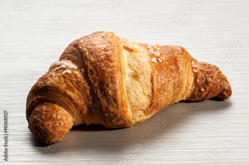 Single croissant on white table