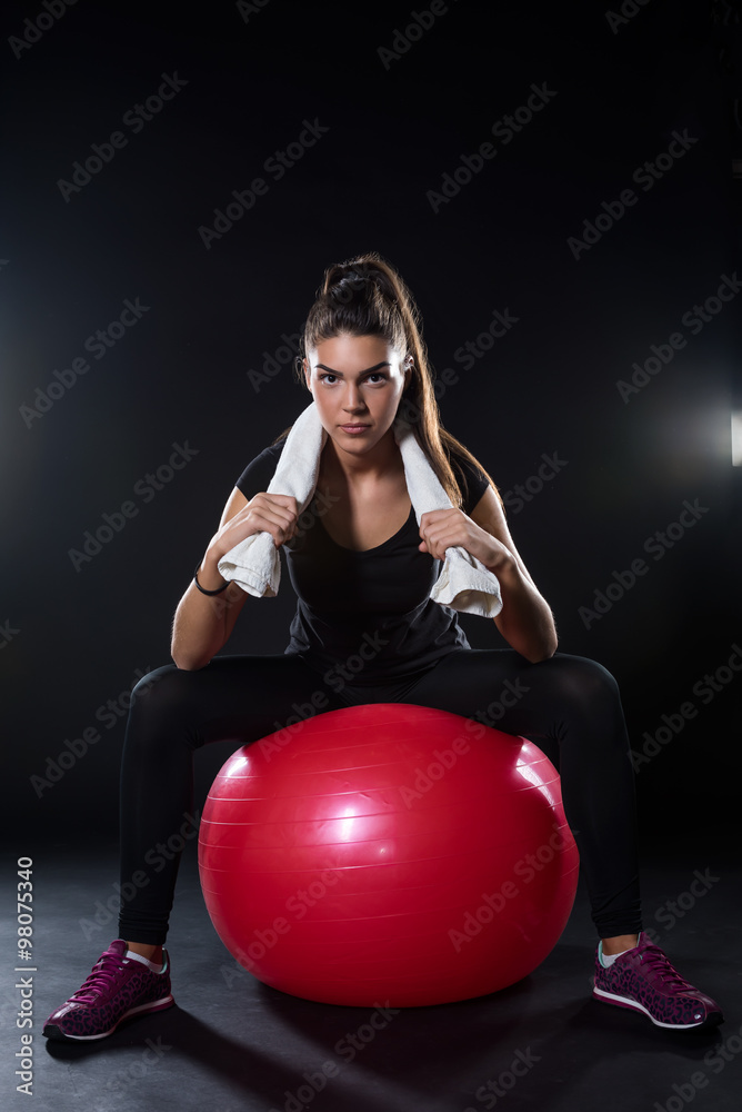 power fitness girl sitting on fitness ball isolated on black