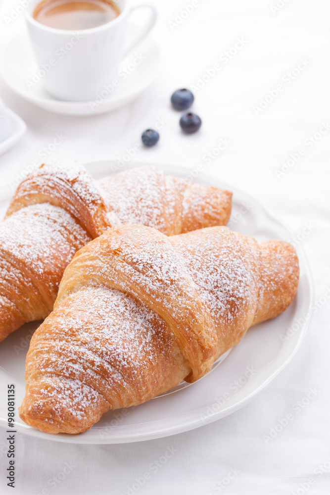 Couple of croissants on a white plate with coffee and berries. Couple of croissants on a white plate with coffee and berries.