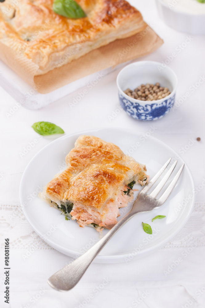 Traditional pie with salmon, spinach and basil on a white table. Traditional pie with salmon, spinach and basil on a white table.