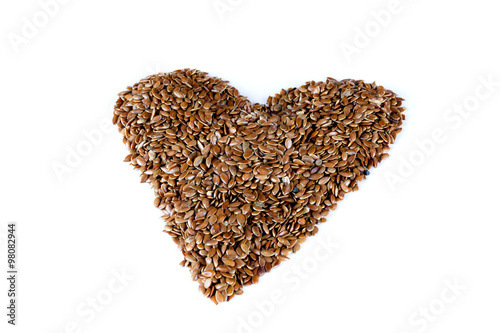 a pile of brown flax seeds in heart shape form on isolated white background © twinsterphoto