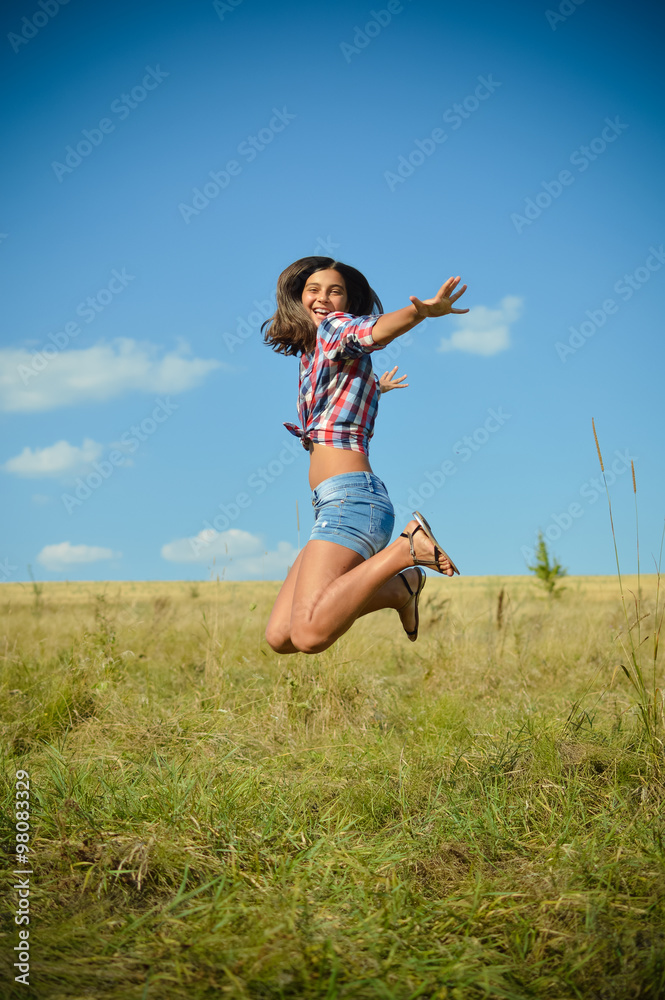 Teenage girl jumping on summer field