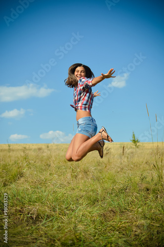 Teenage girl jumping on summer field