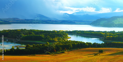 Beautiful landscape, green and yellow meadow and lake with mountain in background. Slovakia, Central Europe. © jozefklopacka