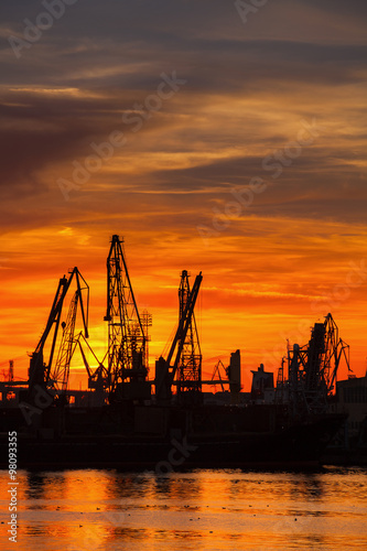 Silhouettes of cranes and cargo ships in port