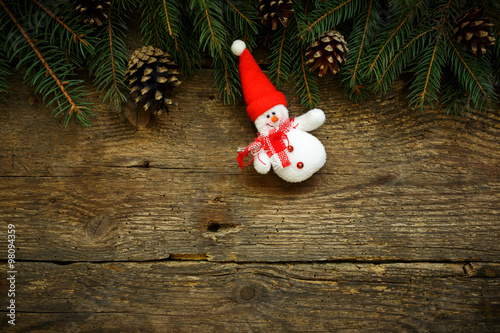 Christmas tree branches with snowman on wooden texture