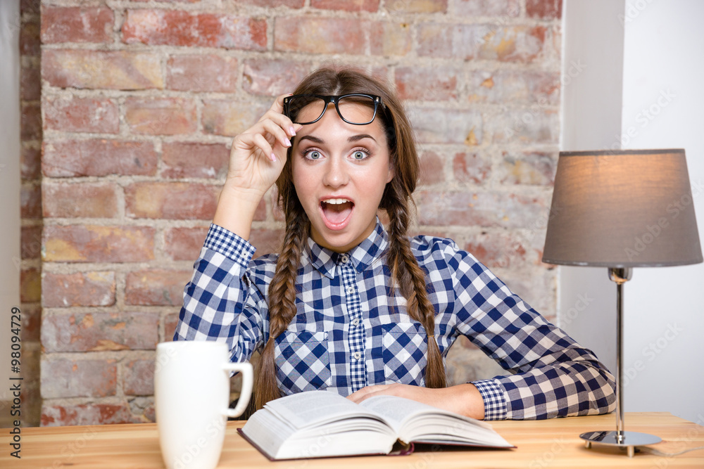 Excited woman sitting at the table with book Excited woman sitting at the table with book