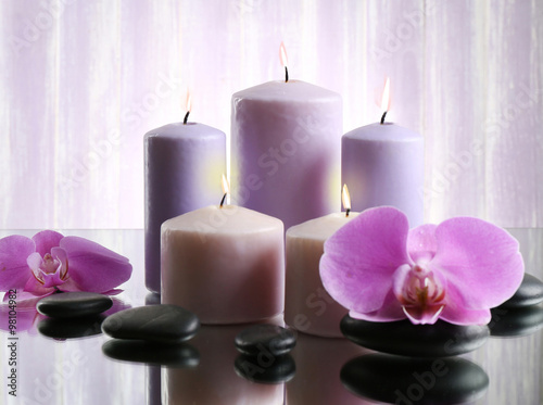 Spa composition with candles, pebbles and flowers on grey background