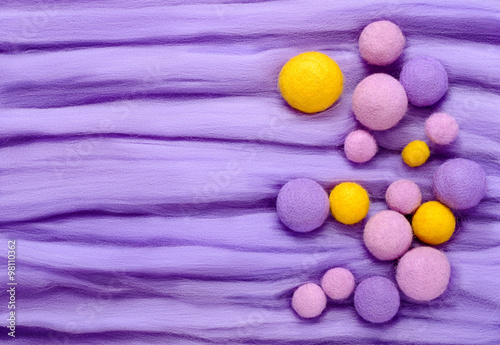 Purple, lilac and yellow beads of different sizes. Background made of wool for felting photo