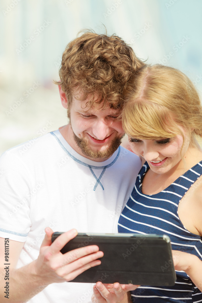 Fototapeta premium Young couple with tablet by seaside outdoor