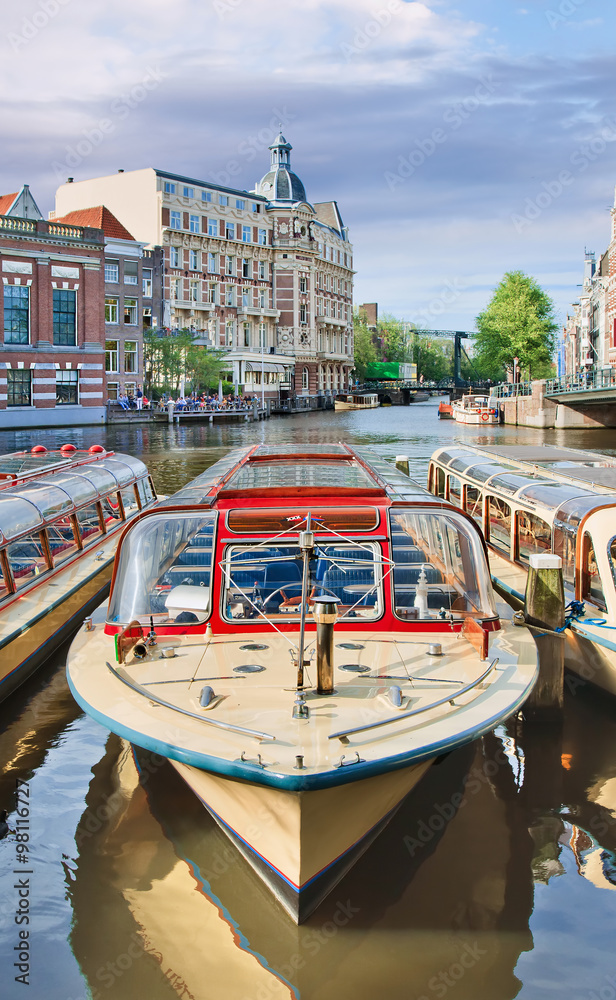 Tour boat with ancient mansion and drawbridge on the background, Amsterdam, Netherlands