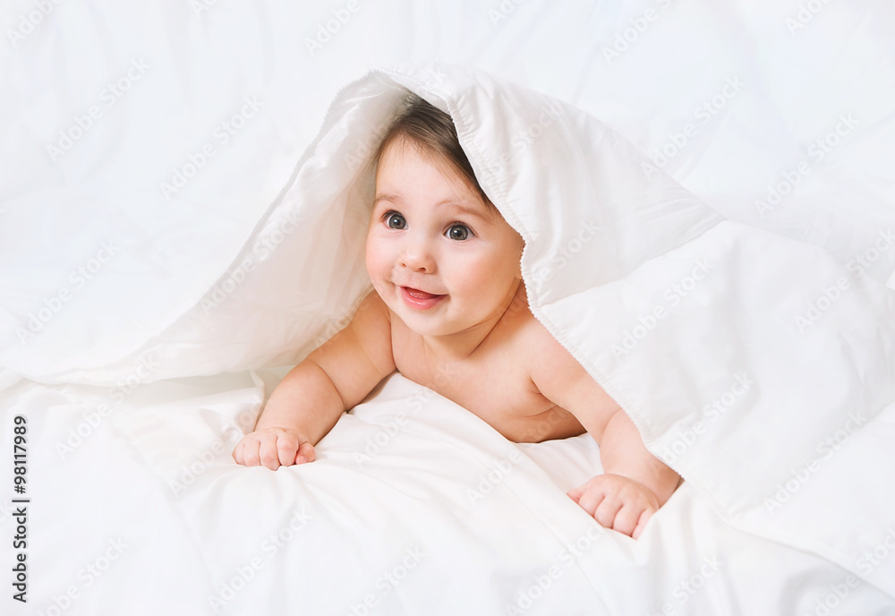 Surprised Baby lies on the bed under the blanket Surprised Baby lies on the bed under the blanket