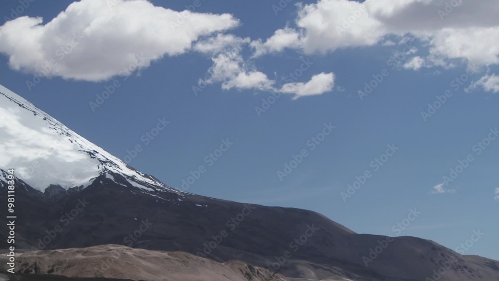 View to the Parinacota volcano snowcapped slopes with blue sky and clouds in Lauca National Park, Chile.