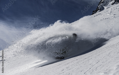 A snowboarder makes a turn in deep powder snow on a sunny winter day in western Austria