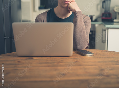 Woman with laptop and smart phone in kitchen