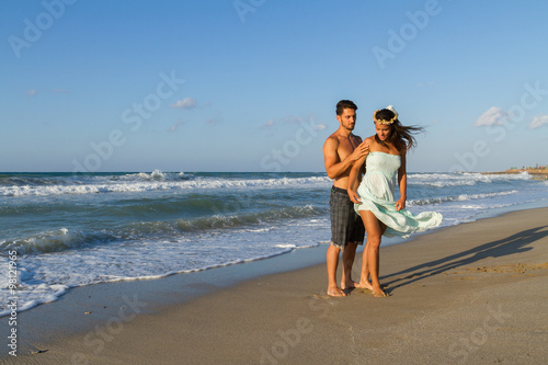 Young couple enjoys walking on a hazy beach at dusk.