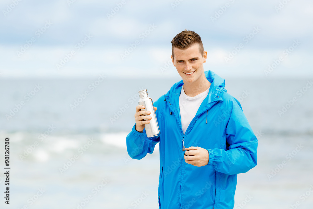 Confident young man holding bottle with water Confident young man holding bottle with water