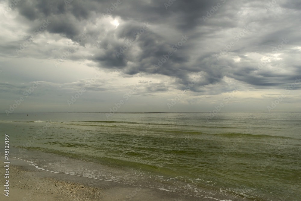 Tropical beach with shallow water and stormy dark sky