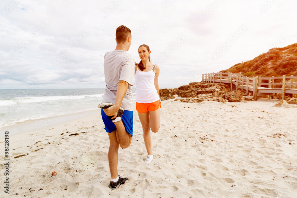 Runners. Young couple exercising and stertching on beach Runners. Young couple exercising and stertching on beach