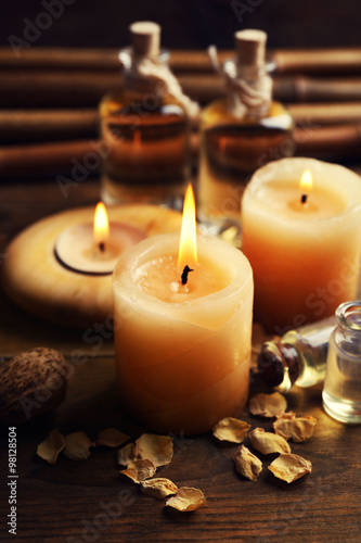 Beautiful decorated composition with candles, pebbles and bamboo on wooden background, close up