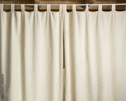 Ivory curtain hanging on a metal rod with the help hinges © koldunova