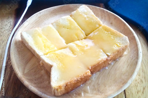 Bread toast and condensed milk on wooden plate