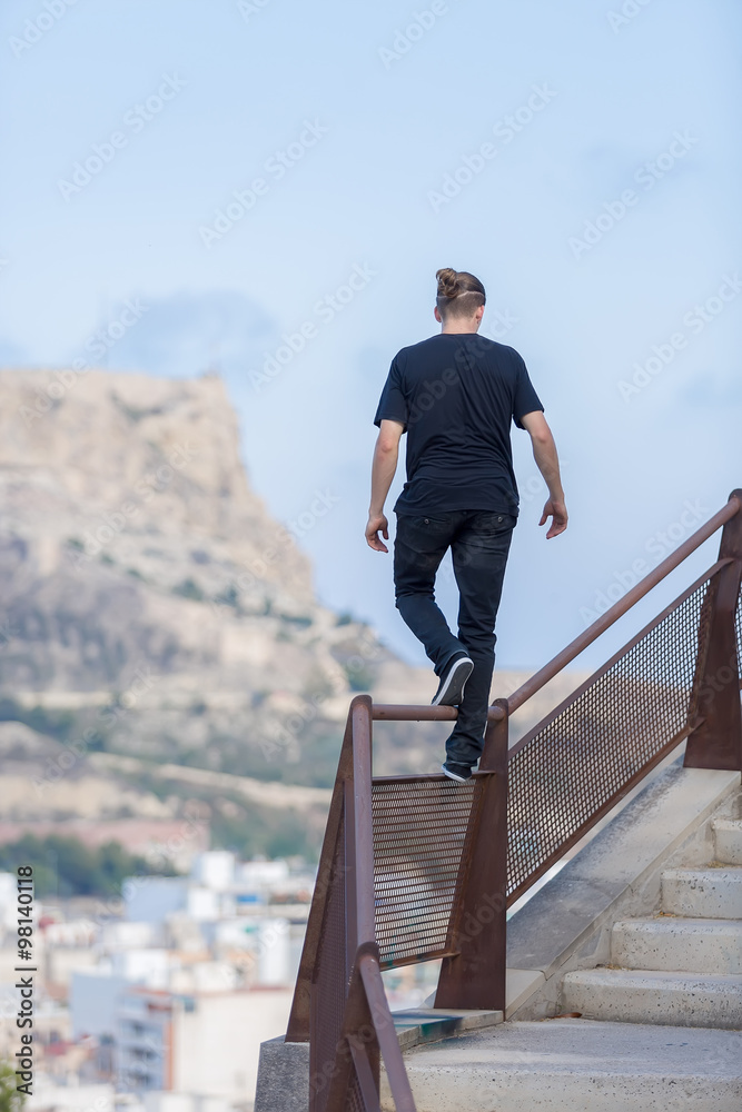 Back view of young athlete walking on railing