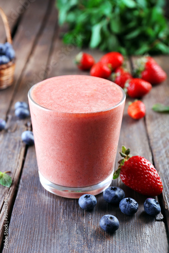 A glass of fresh cold smoothie with berries, on wooden background