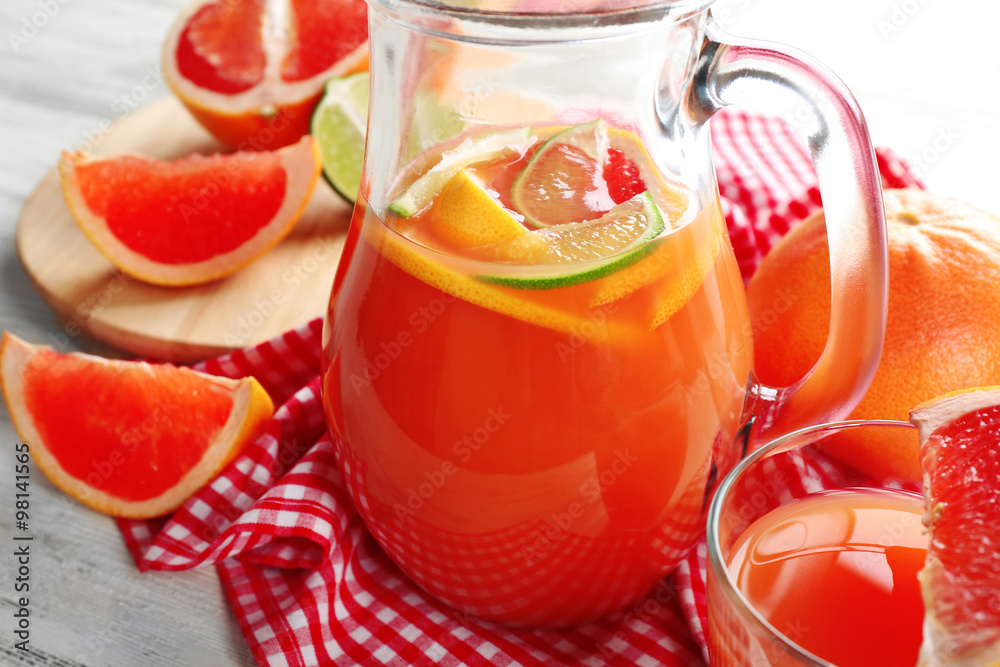 Jar of citrus juice and fresh fruits on light wooden background Jar of citrus juice and fresh fruits on light wooden background