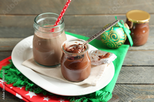 Chocolate dessert in a small glass jars and chocolate milk cocktail on wooden background