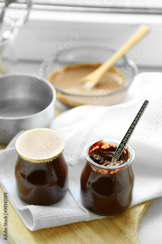 Chocolate dessert in a small glass jars on light wooden background