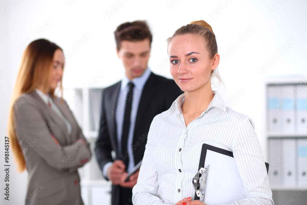 Pretty businesswoman in office with colleagues in the background Pretty businesswoman in office with colleagues in the background