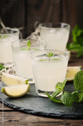 Fresh cocktail with lemon, ice and mint on the vintage table