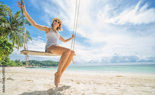 Tropical vacation. Beautiful happy woman swinging on a Tropical beach on Koh Lipe island. Thailand.