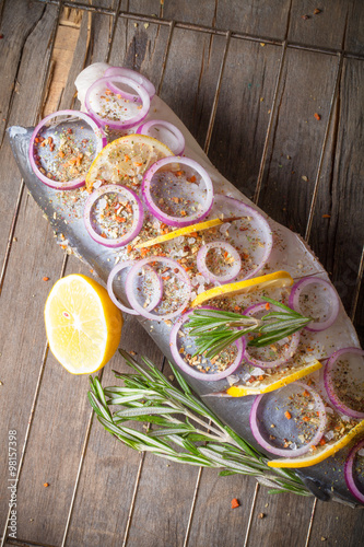 Fish Nelma with lemon, onion and rosemary on a wooden table. Ton photo