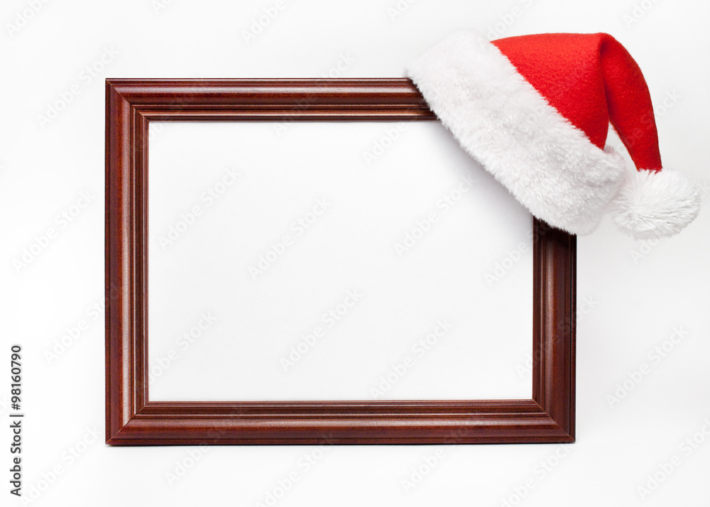 Fototapeta premium Wooden frame for paintings with a Christmas cap on a white background