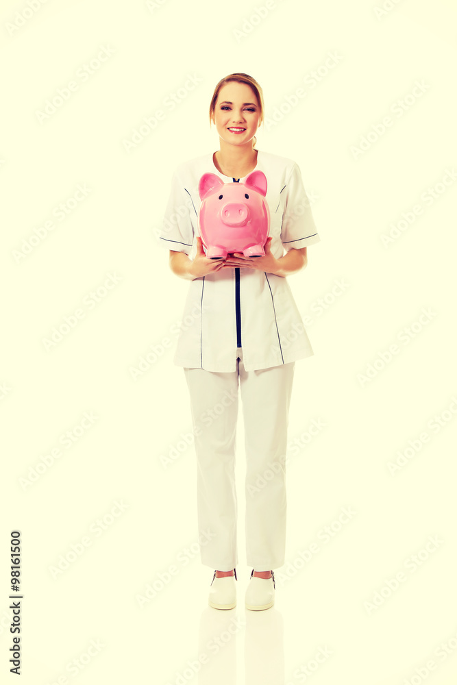 Young female doctor holding a piggybank. Young female doctor holding a piggybank.