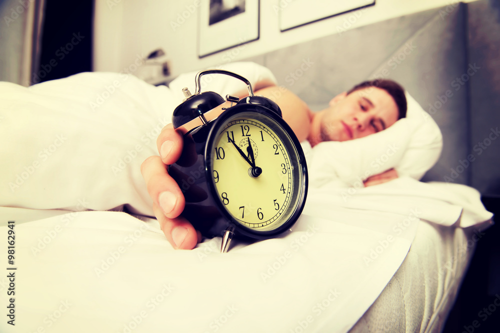 Man with alarm clock in bedroom. Man with alarm clock in bedroom.