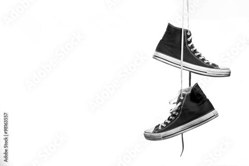 
Black and white shot of pair of sneakers hanging in front of a white background