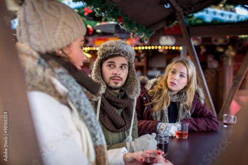 Couple and friend, Friends on a german Christmas market enjoying traditional mullet wine and talk to each other
